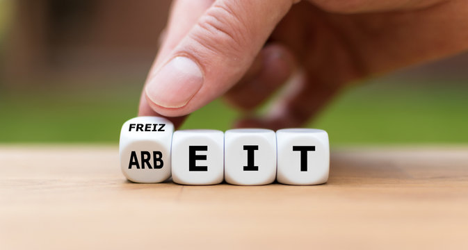 Hand dreht einen W&uuml;rfel und &auml;ndert das Wort "Arbeit" in "Freizeit".