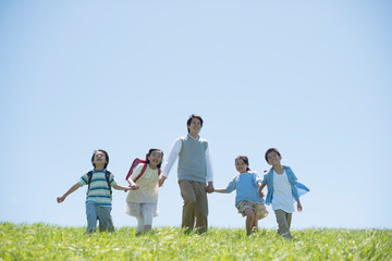 草原で手をつなぐ小学生と先生