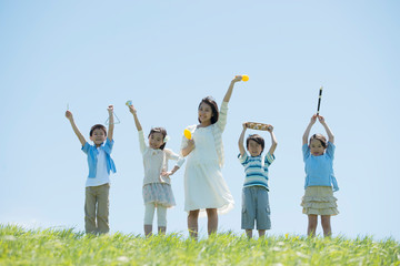 草原で楽器を持ち微笑む小学生と先生