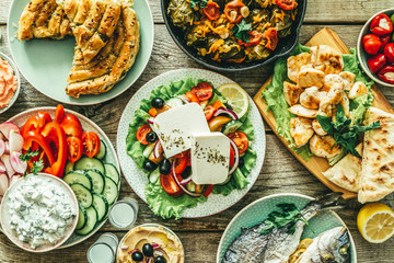 Selection of traditional greek food - salad, meze, pie, fish, tzatziki, dolma on wood background,...