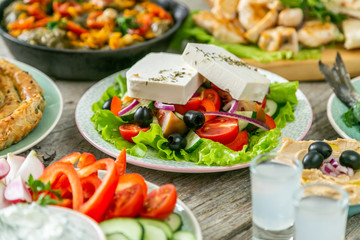 Selection of traditional greek food - salad, meze, pie, fish, tzatziki, dolma on wood background,