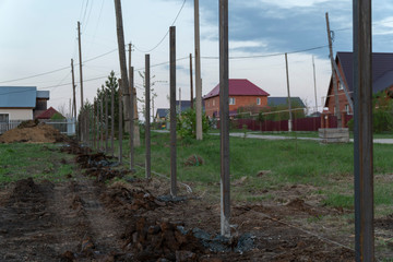 fence construction, concreted metall column. Evening, sunset