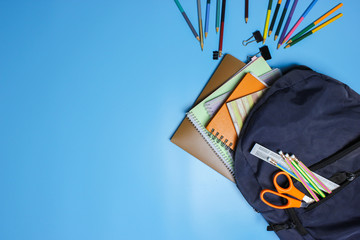 Backpack and supplies school on blue background. Back to school concept. Top view.