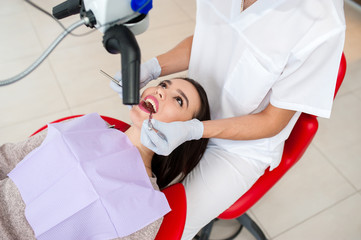 Beautiful girl treats teeth in dentistry.