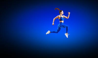 Fototapeta na wymiar Young woman runner in blue sportswear jump in the air.