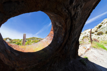 Vista from a rusted old boiler drum on the disused Porth Wen Brickworks looking back towards a brick chimney, Anglesey, North Wales