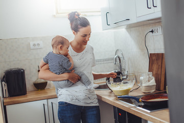 Single mother working at kitchen. Young mother making pancakes.