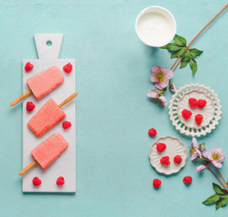 Pink raspberries popsicles ice cream with fresh berries on blue table, top view. Summer food