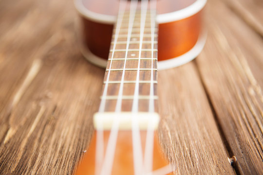 Photo depicts musical instrument ukulele guitar on a wooden table
