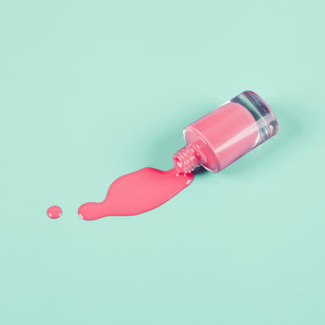 An overhead view of spilled nail polish bottle on mint background