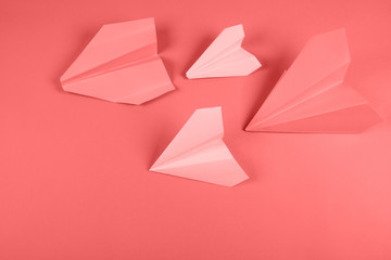 Coral and pink paper airplane on colored background