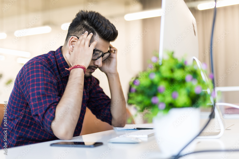 Wall mural tired and worried indian business man at workplace in office