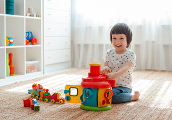 Child playing with colorful toy blocks on the floor in the room Educational toys for young...