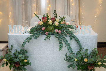 Roses and greenery decorate the main table at a wedding