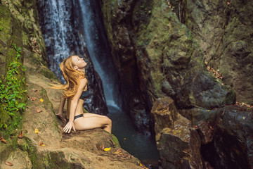 Young beautiful woman standing in the water at the waterfall