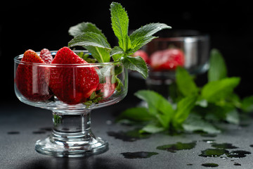 Fresh ripe red strawberries in a glass bowl on a black background