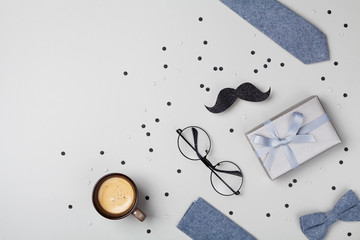Holiday breakfast on Happy Fathers Day with cup of coffee, gift box, glasses, bowtie and moustache top view. Flat lay.