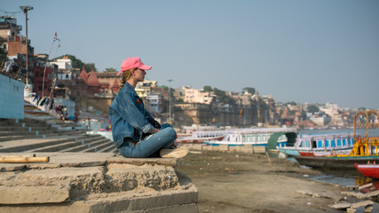 Fototapeta na wymiar Female traveller meditate in front of Ganges River in Varanasi, India