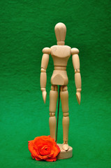 A wooden mannequin display with an orange rose with selective focus