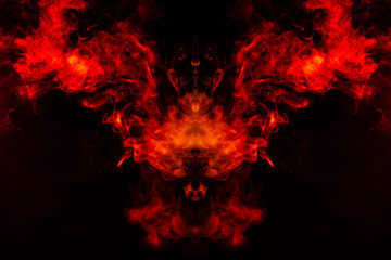 Smoke of different orange and red colors in the form of horror in the shape of the head, face and eye with wings on a black isolated background. Soul and ghost in mystical symbol