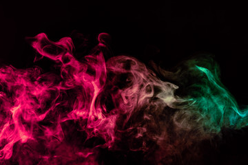 Beautiful column of smoke in the neon bright light of red, green, pink and turquoise on a black background exhaled out of the vape. Nice pattern for printing and backdrop of colored waves.