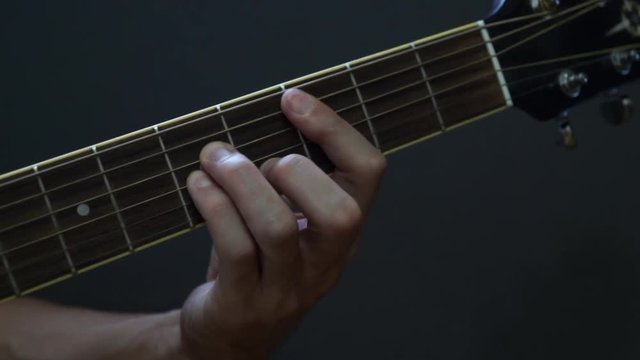 Guitarist playing guitar in studio - close-up of the fingerboard and hand playing chords 