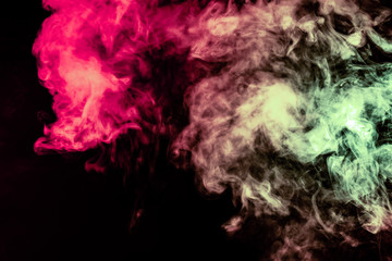 Beautiful column of smoke in the neon bright light of red, green, pink and turquoise on a black background exhaled out of the vape. Nice pattern for printing and backdrop of colored waves.