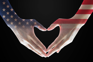 United States of America flag pattern on woman's hands in heart shape on black background