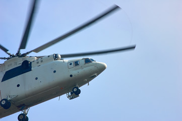 A large helicopter is flying in the blue sky, bottom side view