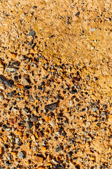 Orange clay with crushed stones scattered on surface.