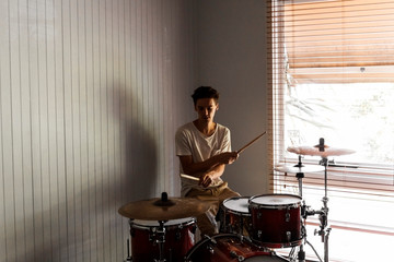 Fototapeta na wymiar Drummer playing difficult cross handed drum pattern on home practise drum kit.