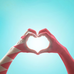 Obraz premium Bahrain flag pattern on people hands in heart shape on mint background