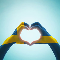 Sweden flag on people heart  shape hands
