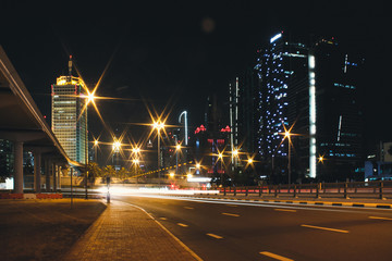 Fototapeta na wymiar Night city Dubai with glowing light from the road and buildings near the metro station line