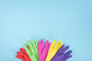 top view of multicolored rubber gloves on blue background with copy space