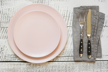 Table place setting with pink plate on white wooden table. Top view.