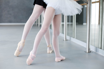 Two ballerinas child girl and woman in ballet pointe shoes. Little kid and adult teacher are...