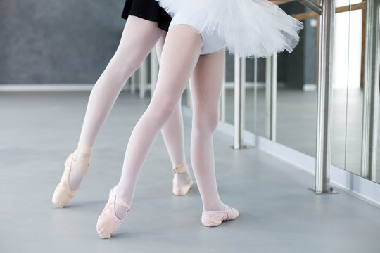 Two ballerinas child girl and woman in ballet pointe shoes. Little kid and adult teacher are studying choreographic position for legs in classical dance school. Practicing for children. Close up.