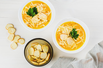 Pumpkin cream soup with croutons and fresh dill and parsley on wooden background, top view