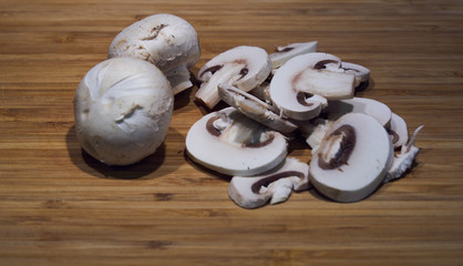 Mushrooms freshly cut into slices with a knife and placed on a wooden board prepared for cooking in the kitchen.