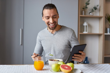 Fototapeta na wymiar Cheerful man using tablet during breakfast