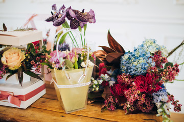 flower abundance. boxes of flowers stand on a wooden table. flower shop. counter in the flower shop. gift for mothers day. flowers for valentines day. flowers on a wooden table.