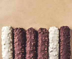 Dark and white chocolate bars with nuts on wrapping paper, copy space, top view