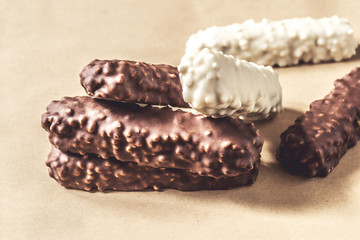 Dark and white chocolate mini bars with nuts on wrapping paper, closeup