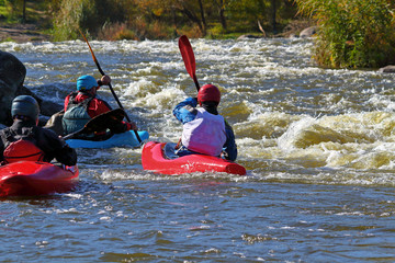 People kayaking on rapids in whtewater. View from the back