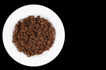 Steamed quinoa on white plate on black background