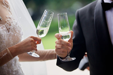 A glass of alcoholic drink in the hands of a couple of lovers.