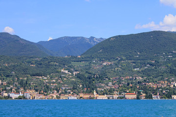 Fototapeta premium Summer landscape on lake Garda Italy with turquoise water medieval town on a green hill