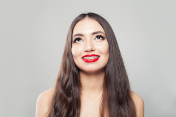 Young woman in braces smiling and looking up on white background