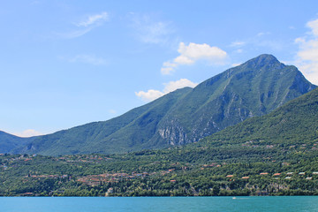 Fototapeta na wymiar Summer landscape on lake Garda Italy with turquoise water and green mountains on the banks